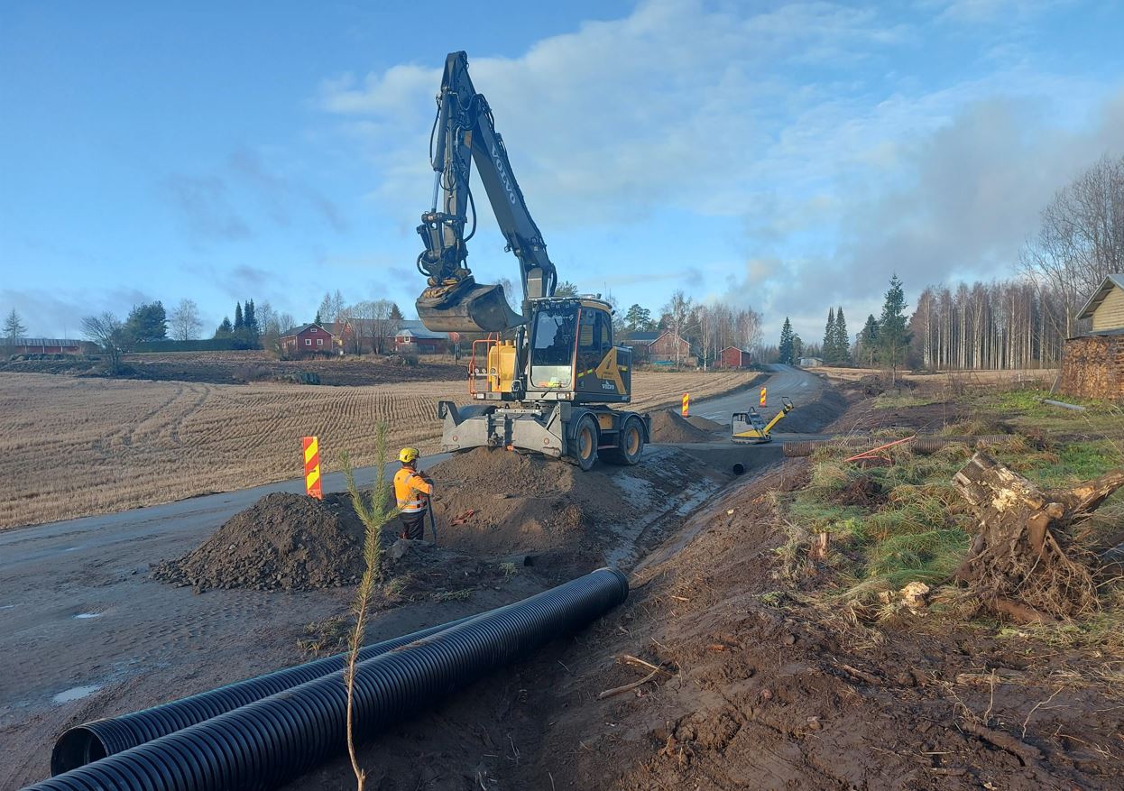 Tien rakennus menossa, tie on avattu kauhakuormaajlla auki ja vieressä on työmies.